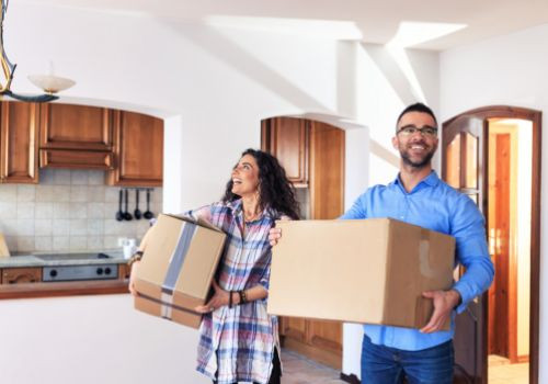Couple moving into house holding cardboard boxes