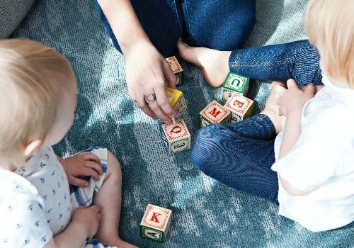 Woman playing blocks with two toddlers
