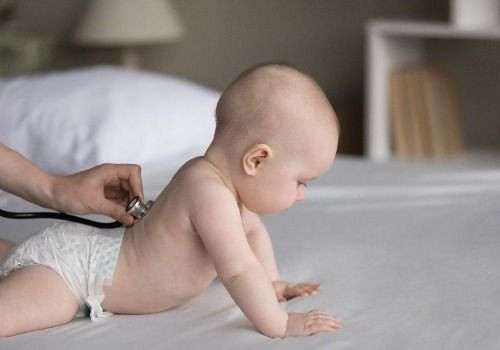 Doctor holding stethoscope on crawling baby